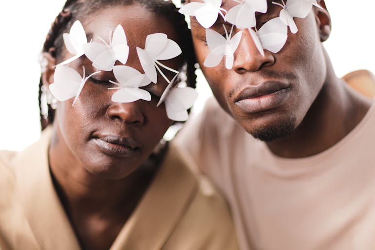 Artistic portrait of a man and woman with paper butterflies over eyes, symbolizing vision.